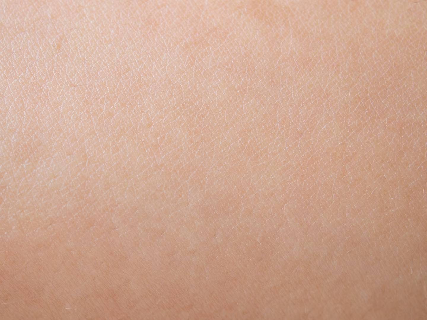 Très gros plan sur une peau humaine saine, montrant en détail sa texture fine et ses pores.