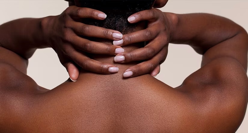  Vue de dos d'une femme noire, ses mains aux ongles soignés posées sur sa nuque.