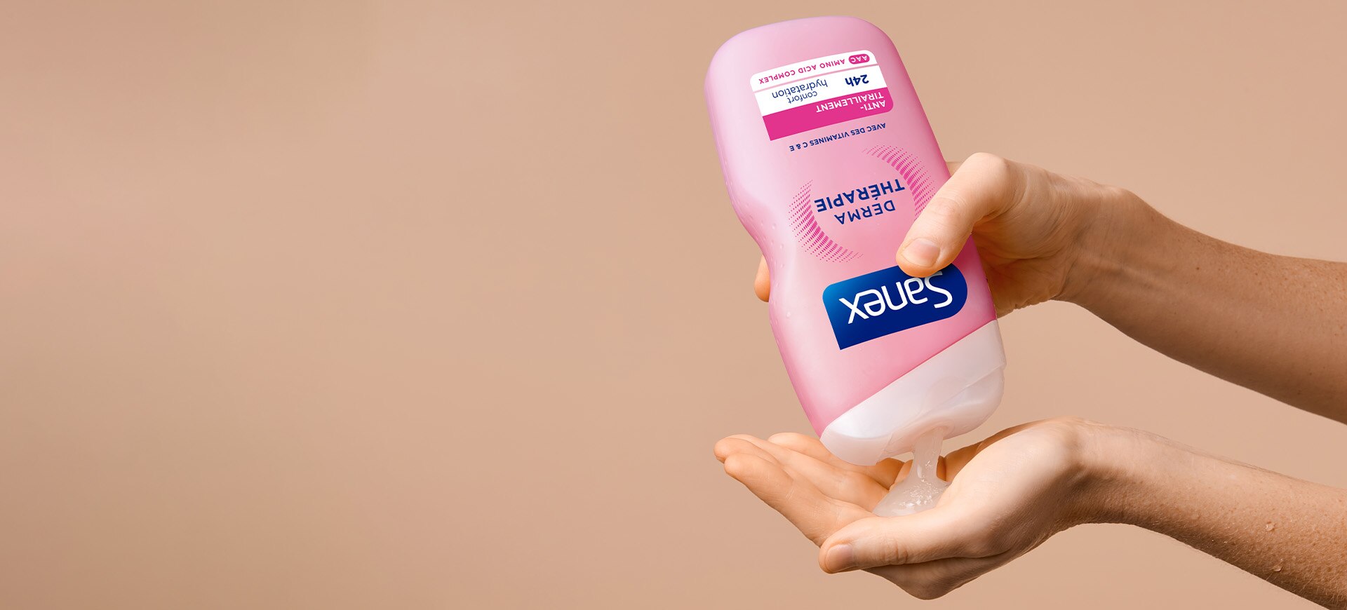 sur fond de couleur chair, gros plan des mains d'une femme en tee-shirt blanc appliquant du Sanex Derma Thérapie sur sa main gauche.