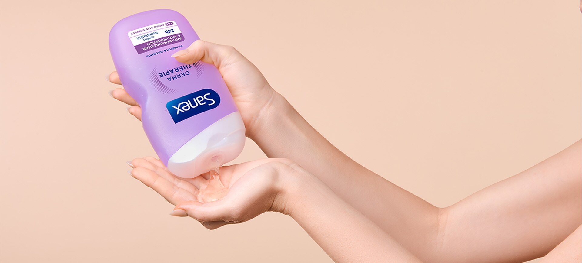 gros plan d'une jeune femme appliquant sur sa main gauche de la Sanex Derma Thérapie pour l'eczéma.