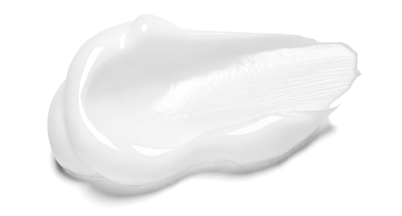 Gros plan sur une noisette de crème blanche onctueuse, montrant sa texture riche et brillante sur un fond blanc.