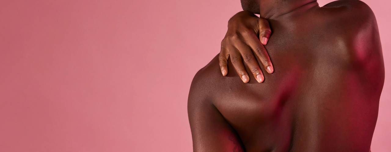 Bannière montrant la vue de dos d'un homme noir, sa main posée sur son épaule, sur un fond rose uni.