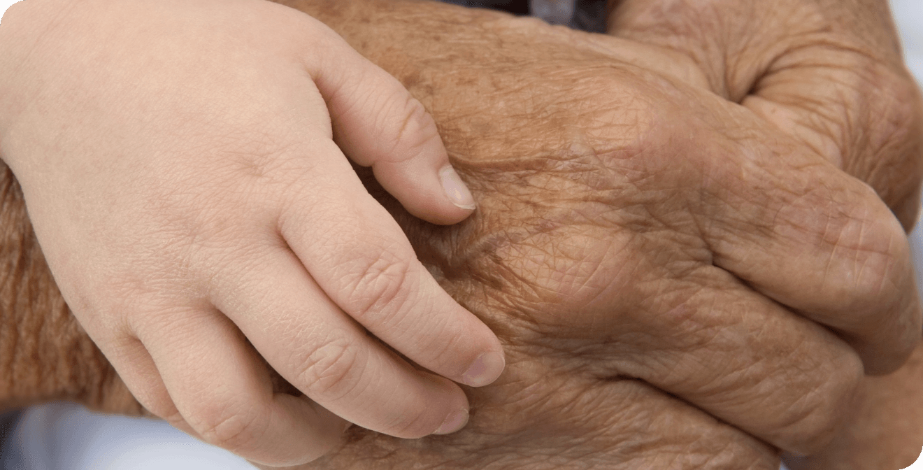 Gros plan sur la main lisse et jeune d'un enfant reposant tendrement sur la main ridée d'une personne âgée.