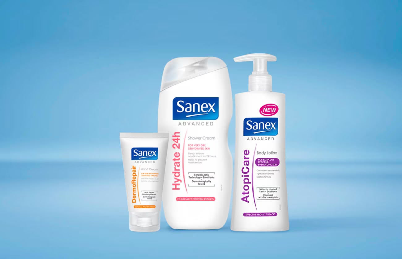 Gamme de produits Sanex Advanced, incluant une crème DermoRepair en tube, une crème de douche Hydrate 24h, et une lotion pour le corps AtopiCare.