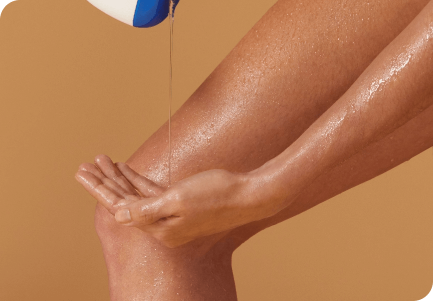 Gros plan sur une personne qui verse un gel douche transparent depuis un flacon sur sa jambe humide et dans le creux de sa main.